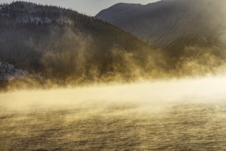 Sunny fog over a lake surrounded by mountains Norway