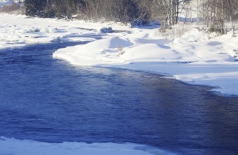 A river that flows through snow-covered landscape surrounded by trees in winter Norway