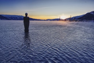 Sunset over a lake with a statue (Havmannen) in the water, Mo i Rana, Norway