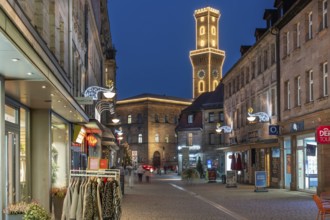 Pedestrian zone in evening lighting, the illuminated town hall tower at the back, blue evening sky,