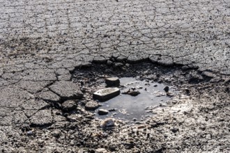 Pothole, asphalt surface, floor, with many small cracks, roadway, parking lot