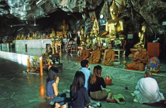 Buddha statue, monks and believers praying, Wat Tam Sua monastery near Krabi, Thailand, December