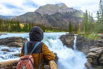 Tourist wearing a backpack and hooded jacket admiring the breathtaking view of powerful athabasca