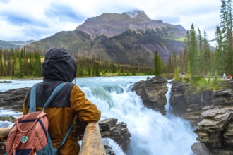 Backpacker enjoying the breathtaking view of athabasca falls cascading through the rugged landscape
