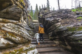 Mother and child walking up stairs among rocks and trees at athabasca falls in jasper national