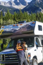 Father and son showing thumbs up, enjoying their rv trip in the majestic canadian rockies near