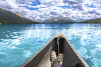 Turquoise maligne lake and surrounding mountains reflecting in the calm water with a person wearing