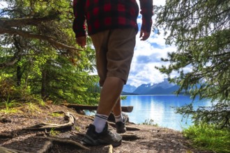 Hiker walking along a forest path toward maligne lake's turquoise waters, framed by a mountain