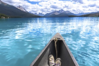 Hiking boots inside a canoe navigating the turquoise waters of maligne lake with its surrounding