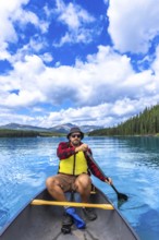 Tourist paddling a canoe in maligne lake under a beautiful cloudy sky, enjoying the turquoise water