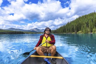 Tourist paddling a canoe on turquoise maligne lake with spirit island in the distance, enjoying the