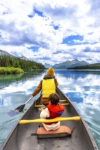 Tourists wearing life jackets are paddling a canoe on beautiful maligne lake in jasper national