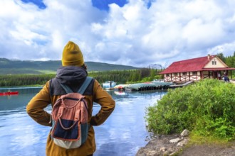 Female tourist wearing a backpack standing on the shore of maligne lake, admiring the iconic