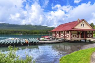 Colorful canoes and kayaks resting on a wooden dock in front of a boathouse on the beautiful