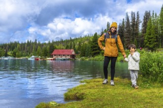 Mother and son holding hands, enjoying a scenic view of maligne lake boathouse in jasper national