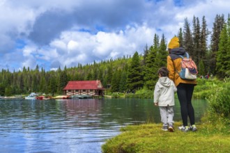 Mother and son enjoying the stunning view of the iconic boathouse on maligne lake, surrounded by