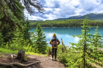 Female hiker with a backpack admiring the stunning turquoise waters of maligne lake, surrounded by