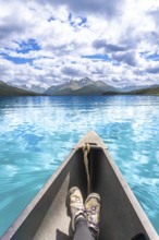 Tourist enjoys stunning view of turquoise water and mountain range while paddling canoe on maligne