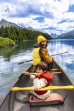 Mother and son are paddling a canoe on beautiful maligne lake in jasper national park, enjoying the