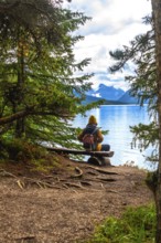 Hiker sitting on a wooden bench, admiring the breathtaking view of maligne lake and the surrounding
