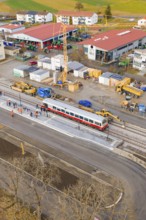 A train passes a large construction site with workers and a crane, historic event, first test run