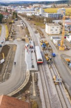 A construction site at a train station with construction work, cranes and a train. Residential