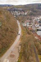A train travels along tracks in a hilly urban landscape with numerous buildings, historic event,