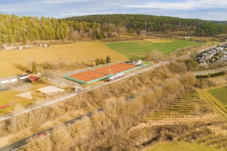 View of tennis courts next to a train line in rural surroundings, historic event, first test run