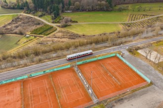 Aerial view of tennis courts next to a train line, historic event, first test run with a passenger