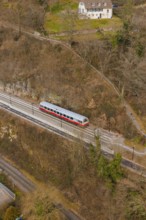 A train travels on a track through wooded hills in a wintry landscape, historic event, first test