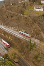 Train on tracks next to wooded hills with buildings in a wintry landscape, historic event, first