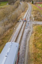 View along the railway tracks with a train and several construction workers on the rails, historic