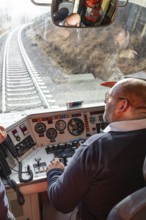 Train driver steers the train from a modern cockpit while traveling on rails, historic event, first