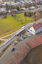 A train at a train station in an urban area with parked cars, historic event, first test run with a