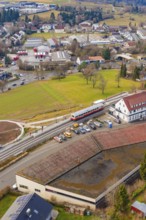 A train stops at a train station in a small town area with residential buildings, historic event,
