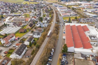 Train on rails in a suburb with residential buildings and industrial facilities, surrounded by