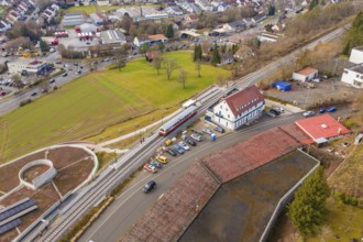 A train stops at a station building in an urban and green area, historic event, first test run with