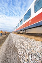Perspective view of a moving train on rails under a blue sky with clouds, historical event, first