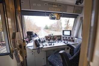 Train driver's cab with various control elements and view of the line through windows, historic
