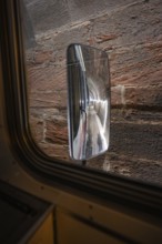 View through a train window of an exterior mirror reflecting the tunnel wall, historic event, first