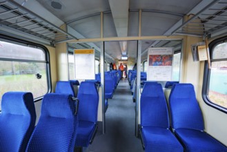 Neatly arranged blue seats inside a train with lots of daylight, historic event, first test run