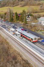 Train at the train station, surrounded by trees and small houses in a wintry landscape, historic