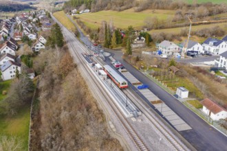 Railway station in rural area with train and rail, surrounded by houses and trees in an autumnal