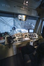 The train goes through a tunnel, the driver's cab with control panel is visible in the foreground,
