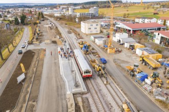 A construction site for a new station with a train, surrounded by construction and cranes, historic
