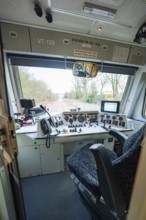 Driver's cab of a train with control elements and screens, view of tracks outside, historic event,