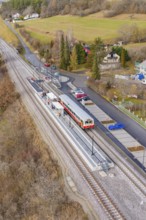 Small train station in a rural area with train, rails and surrounding countryside in autumn colors,