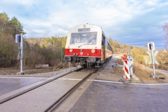 Train on a rail crossing, surrounded by trees, under a cloudy sky, historic event, first test run