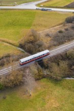 A train crosses a bridge over a river, surrounded by trees in a rural landscape, historic event,