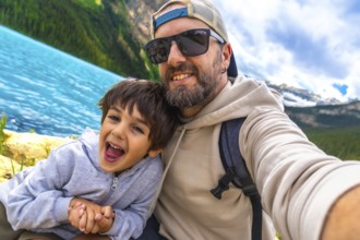 Happy father and son capturing a selfie by the turquoise waters of lake louise, surrounded by